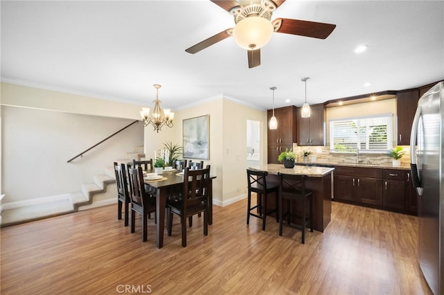16660 Spruce Cir, Fountain Valley, CA 92708 - dining area featuring stairs, light wood finished floors, a chandelier, crown molding, and a ceiling fan