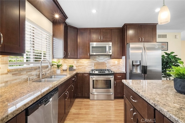 16660 Spruce Cir, Fountain Valley, CA 92708 - kitchen featuring appliances with stainless steel finishes, light wood finished floors, light stone countertops, dark brown cabinetry, and decorative backsplash
