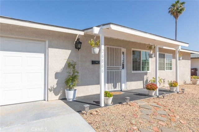 26866 Oakmont Dr, Menifee, CA 92586 - property entrance with stucco siding, a garage, concrete driveway, and a porch