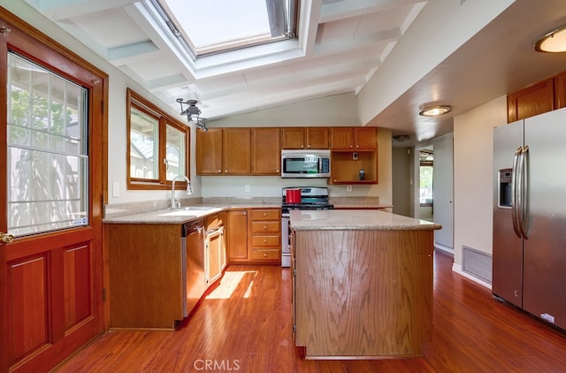 20606 Skouras Dr, Winnetka, CA 91306 - kitchen featuring stainless steel appliances, vaulted ceiling, a skylight, a center island, and wood finished floors
