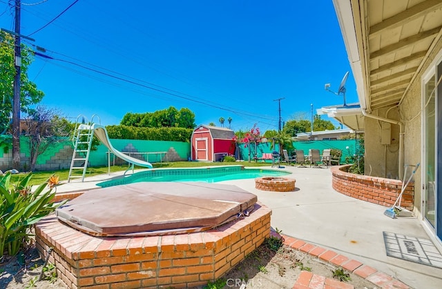20606 Skouras Dr, Winnetka, CA 91306 - view of swimming pool featuring a covered hot tub, a water slide, a patio area, a fenced backyard, and a storage unit