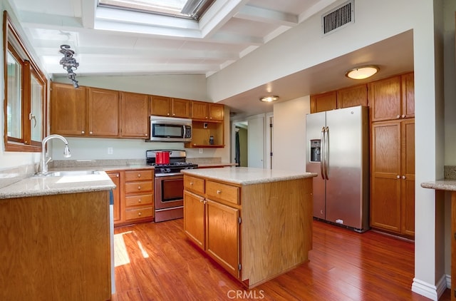 20606 Skouras Dr, Winnetka, CA 91306 - kitchen with appliances with stainless steel finishes, light wood-style floors, a kitchen island, lofted ceiling, and brown cabinets