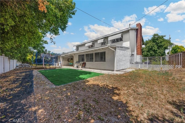 1411 Woodcrest Ave, La Habra, CA 90631 - rear view of house featuring a trampoline, a fenced backyard, stucco siding, and a patio