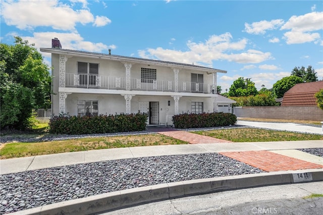 1411 Woodcrest Ave, La Habra, CA 90631 - view of front facade featuring a balcony, a chimney, stucco siding, and driveway