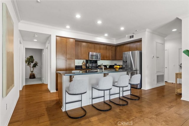 13028 Central Ave Unit 202, Hawthorne, CA 90250 - kitchen with appliances with stainless steel finishes, ornamental molding, a kitchen island with sink, dark wood-style floors, and dark countertops