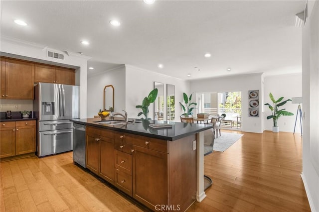 13028 Central Ave Unit 202, Hawthorne, CA 90250 - kitchen featuring appliances with stainless steel finishes, dark countertops, light wood-type flooring, brown cabinetry, and a center island with sink