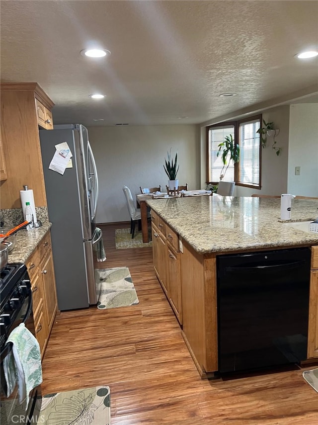 9535 Timberlane Ave, Hesperia, CA 92345 - kitchen with freestanding refrigerator, black dishwasher, light wood-style flooring, stove, and a center island