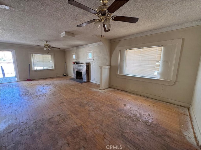 29095 Arrowhead Ave, Barstow, CA 92311 - unfurnished living room with hardwood / wood-style floors, a ceiling fan, crown molding, a textured ceiling, and a brick fireplace