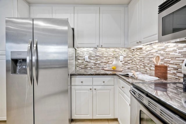 9263 Regents Rd Unit B106, La Jolla, CA 92037 - kitchen with appliances with stainless steel finishes, white cabinetry, tasteful backsplash, and dark stone counters