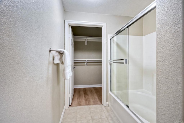 9263 Regents Rd Unit B106, La Jolla, CA 92037 - full bathroom featuring a textured wall, shower / bath combination with glass door, tile patterned floors, and a walk in closet