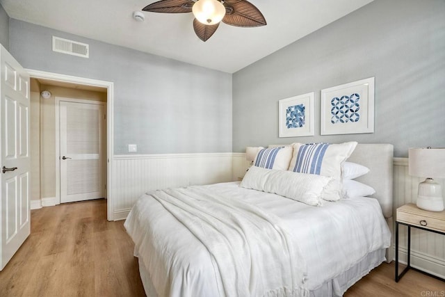 9263 Regents Rd Unit B106, La Jolla, CA 92037 - bedroom featuring wood finished floors, a wainscoted wall, and a ceiling fan