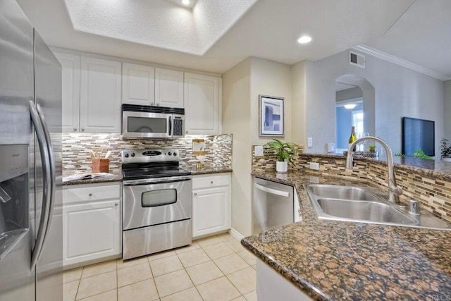 9263 Regents Rd Unit B106, La Jolla, CA 92037 - kitchen featuring appliances with stainless steel finishes, arched walkways, white cabinetry, and crown molding