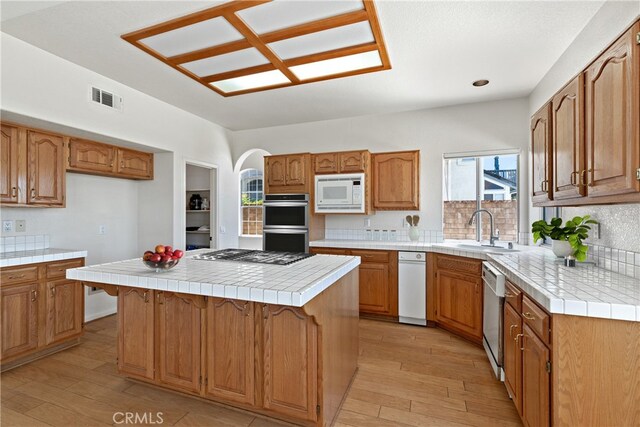 31794 Corte Rosario, Temecula, CA 92592 - kitchen featuring appliances with stainless steel finishes, light wood-style flooring, a center island, and backsplash