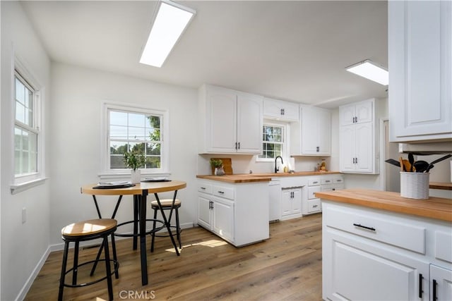 8150 Ocean View Ave, Whittier, CA 90602 - kitchen featuring butcher block counters, healthy amount of natural light, wood finished floors, and white cabinets
