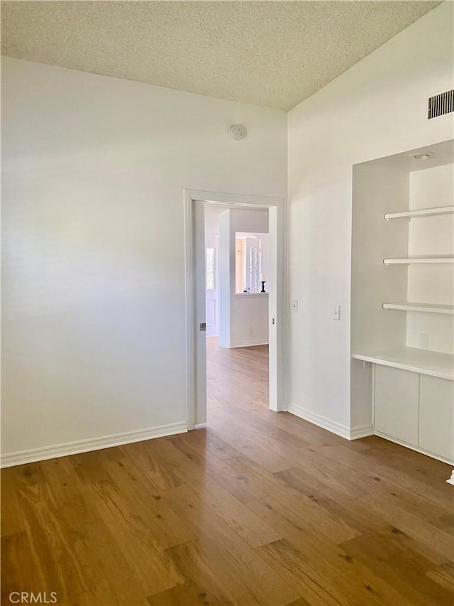 1830 Sunningdale Rd Unit M14-G, Seal Beach, CA 90740 - empty room with wood finished floors, a textured ceiling, and a smoke detector