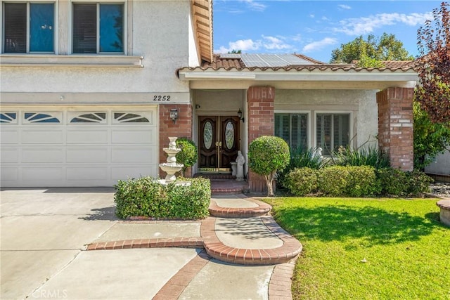 2252 Verbena Ave, Upland, CA 91784 - view of exterior entry featuring stucco siding, a yard, an attached garage, driveway, and a tile roof