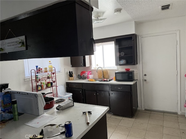 1108 N Rinaldi St, Visalia, CA 93291 - kitchen featuring black microwave, dark cabinets, light countertops, a textured ceiling, and light tile patterned floors