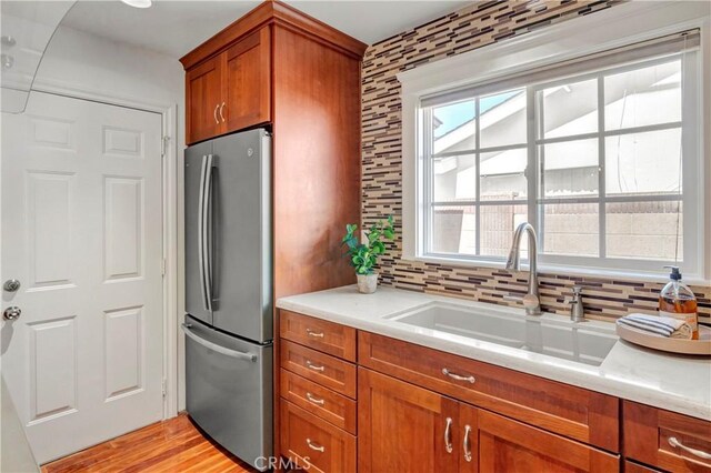 6232 Richmond Ave, Garden Grove, CA 92845 - kitchen with freestanding refrigerator, brown cabinetry, tasteful backsplash, light countertops, and light wood-style flooring