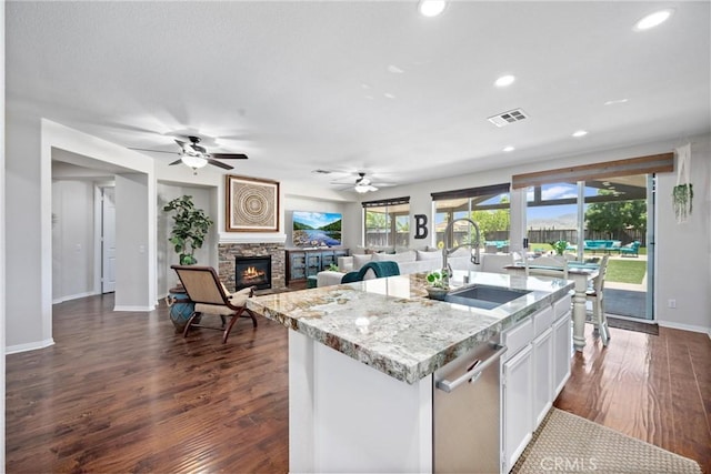 19205 Sterling Hill Ln, Perris, CA 92570 - kitchen featuring dishwasher, a fireplace, dark wood-style flooring, an island with sink, and white cabinets