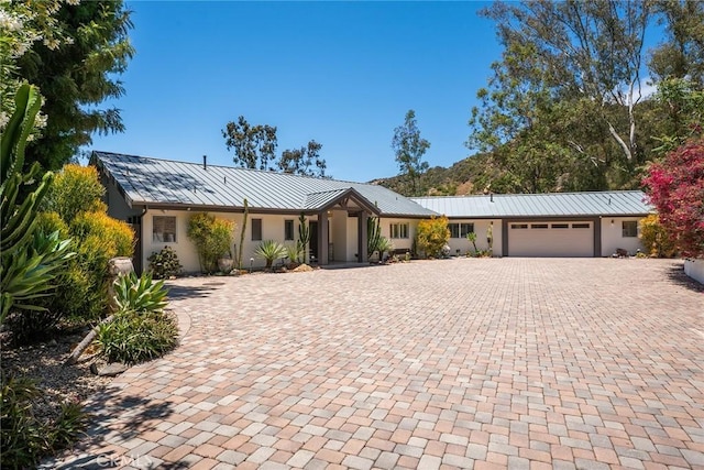 24311 Sylvan Glen Rd, Calabasas, CA 91302 - ranch-style house featuring stucco siding, decorative driveway, a garage, a standing seam roof, and a metal roof