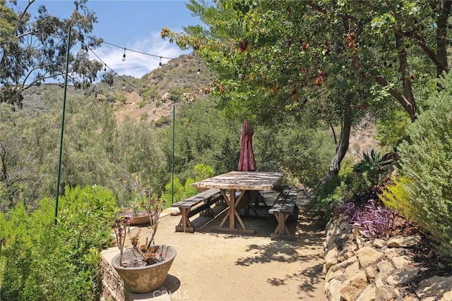 24311 Sylvan Glen Rd, Calabasas, CA 91302 - view of patio featuring outdoor dining area, a wooded view, and a mountain view