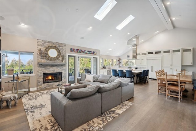 24311 Sylvan Glen Rd, Calabasas, CA 91302 - living area featuring a stone fireplace, high vaulted ceiling, beam ceiling, wood finished floors, and plenty of natural light