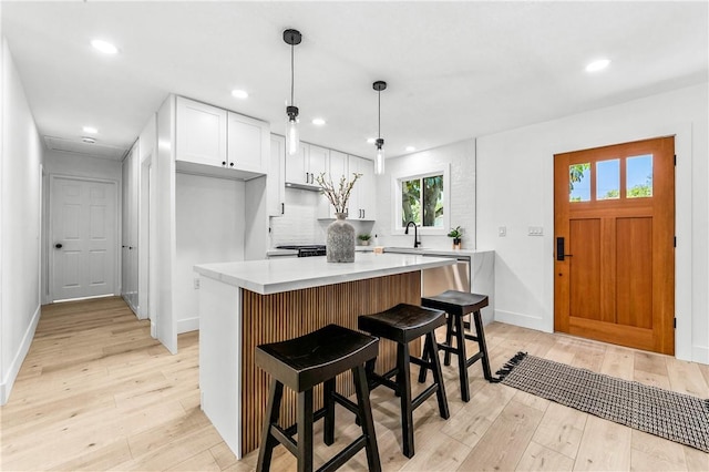 6816 E Driscoll St, Long Beach, CA 90815 - kitchen featuring light wood-style floors, light countertops, white cabinetry, a center island, and recessed lighting