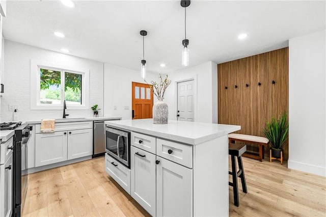 6816 E Driscoll St, Long Beach, CA 90815 - kitchen with appliances with stainless steel finishes, recessed lighting, a breakfast bar, light wood-type flooring, and white cabinetry