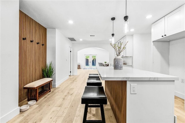 6816 E Driscoll St, Long Beach, CA 90815 - kitchen featuring arched walkways, white cabinets, light wood-style floors, recessed lighting, and light countertops