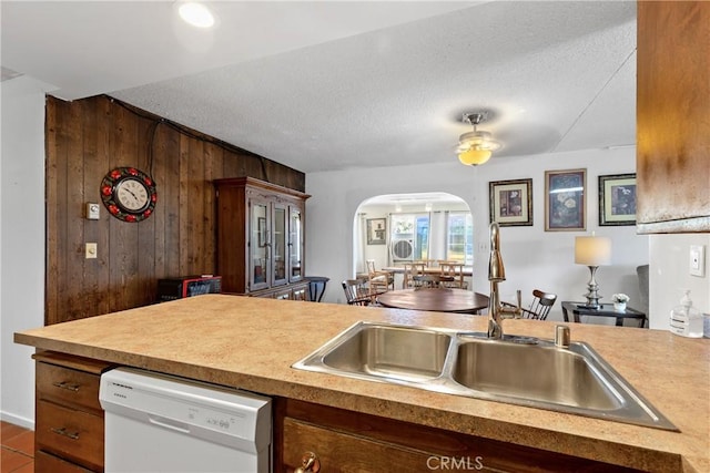 57795 El Dorado Dr, Yucca Valley, CA 92284 - kitchen with white dishwasher, arched walkways, wooden walls, light countertops, and ceiling fan