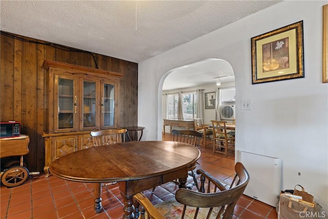 57795 El Dorado Dr, Yucca Valley, CA 92284 - dining room featuring arched walkways, tile patterned floors, wooden walls, and a textured ceiling