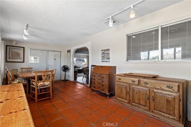 57795 El Dorado Dr, Yucca Valley, CA 92284 - dining area featuring track lighting, arched walkways, a textured ceiling, and dark tile patterned flooring