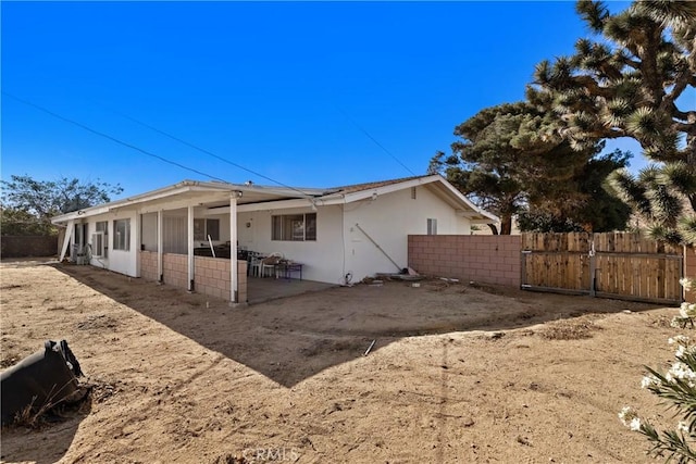 57795 El Dorado Dr, Yucca Valley, CA 92284 - back of house with stucco siding, a patio area, a gate, and solar panels