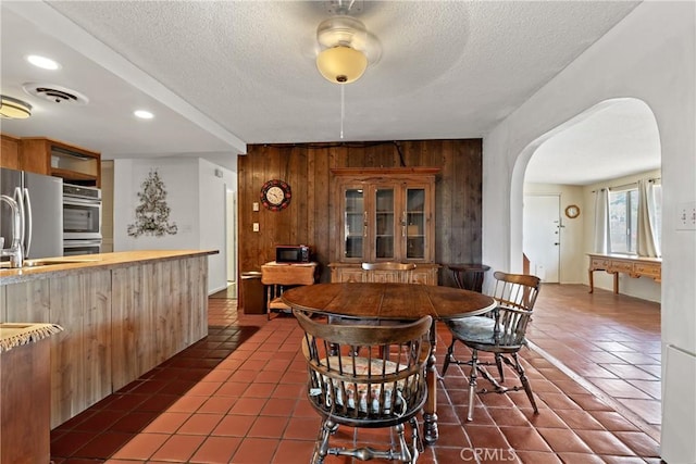 57795 El Dorado Dr, Yucca Valley, CA 92284 - dining area with arched walkways, wood walls, dark tile patterned floors, a textured ceiling, and recessed lighting