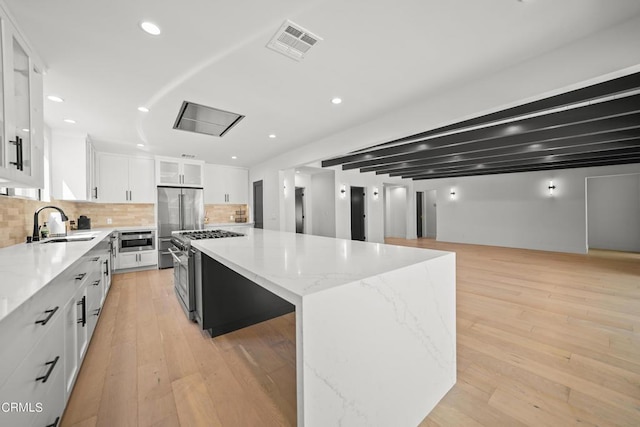 9518 Forbes Ave, Northridge, CA 91343 - kitchen featuring premium appliances, a spacious island, white cabinets, tasteful backsplash, and recessed lighting