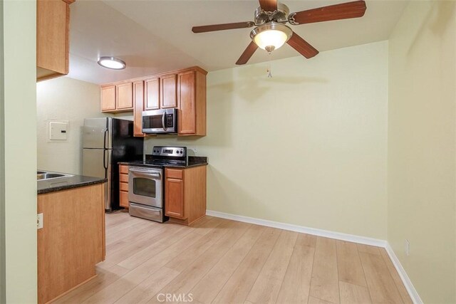 1345 Cabrillo Park Dr Unit A06, Santa Ana, CA 92701 - kitchen featuring appliances with stainless steel finishes, dark countertops, light wood-style flooring, and ceiling fan