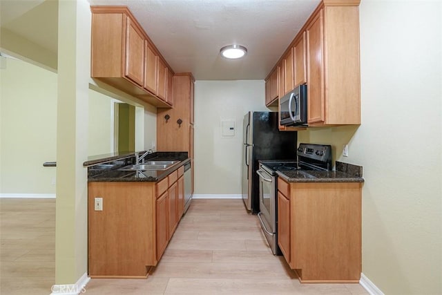 1345 Cabrillo Park Dr Unit A06, Santa Ana, CA 92701 - kitchen featuring appliances with stainless steel finishes, dark stone counters, light wood-style flooring, and brown cabinetry