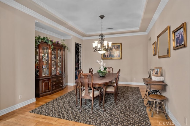 13812 Breeders Cup Dr, Rancho Cucamonga, CA 91739 - dining space featuring a chandelier, a raised ceiling, light wood finished floors, and crown molding