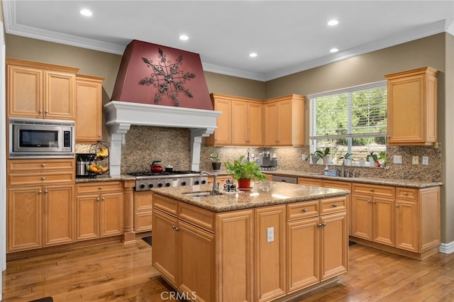 13812 Breeders Cup Dr, Rancho Cucamonga, CA 91739 - kitchen with stainless steel appliances, light wood finished floors, backsplash, crown molding, and an island with sink