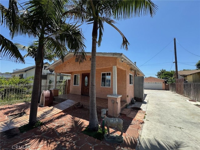 1442 E 76th Pl, Los Angeles, CA 90001 - view of front of house featuring stucco siding, a detached garage, and an outbuilding