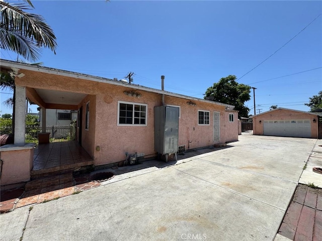 1442 E 76th Pl, Los Angeles, CA 90001 - rear view of house with stucco siding, a garage, and an outbuilding