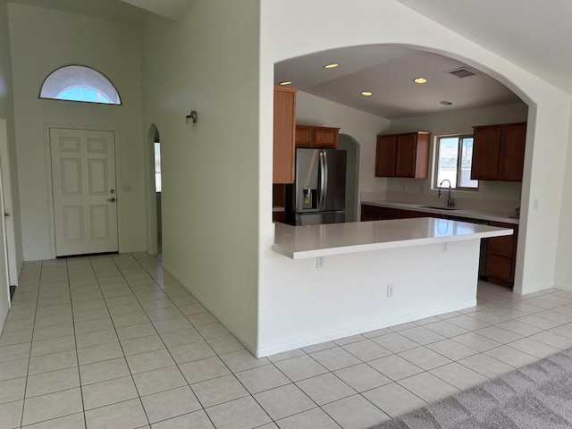 31100 Desert Palm Dr, Thousand Palms, CA 92276 - kitchen with stainless steel refrigerator with ice dispenser, light countertops, a peninsula, light tile patterned floors, and arched walkways