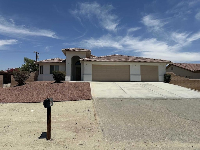 31100 Desert Palm Dr, Thousand Palms, CA 92276 - mediterranean / spanish home with an attached garage, concrete driveway, a tile roof, and stucco siding