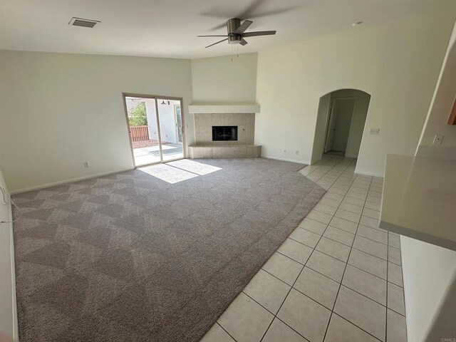 31100 Desert Palm Dr, Thousand Palms, CA 92276 - unfurnished living room featuring a ceiling fan, arched walkways, light carpet, light tile patterned floors, and a fireplace