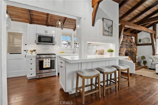 135 Turquoise Ave, Newport Beach, CA 92662 - kitchen featuring appliances with stainless steel finishes, a wooden ceiling with exposed beams, dark wood-style floors, light countertops, and a breakfast bar area
