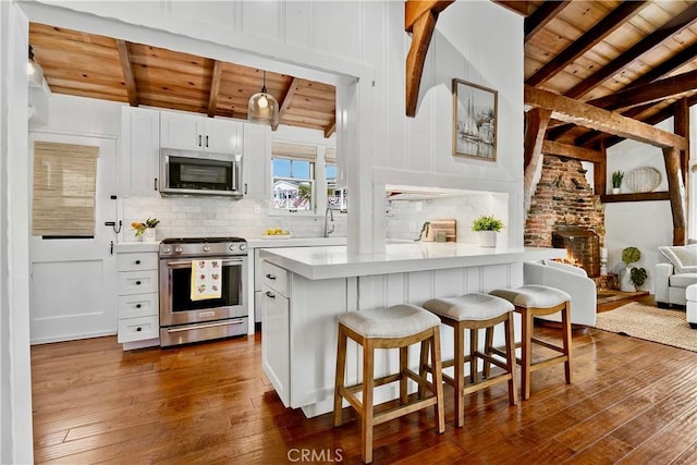 135 Turquoise Ave, Newport Beach, CA 92662 - kitchen featuring stainless steel appliances, wooden ceiling, dark wood-style flooring, light countertops, and a kitchen breakfast bar