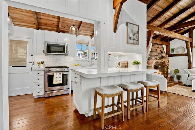 135 Turquoise Ave, Newport Beach, CA 92662 - kitchen with stainless steel appliances, wood ceiling, dark wood-style flooring, light countertops, and a breakfast bar area