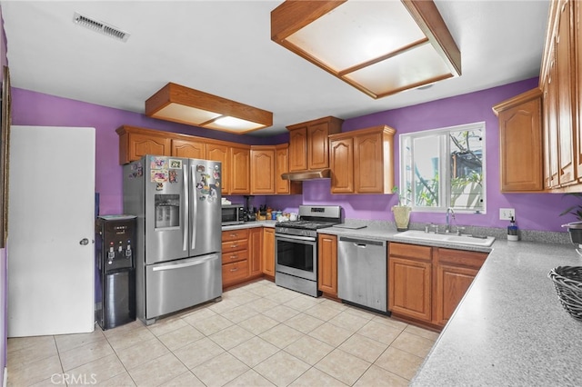 1002 N Iroquois Ave, Anaheim, CA 92801 - kitchen with appliances with stainless steel finishes, light countertops, brown cabinetry, under cabinet range hood, and light tile patterned flooring