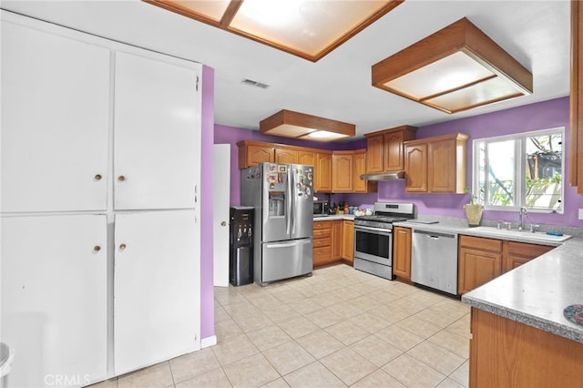 1002 N Iroquois Ave, Anaheim, CA 92801 - kitchen featuring stainless steel appliances, under cabinet range hood, brown cabinets, light tile patterned floors, and light countertops