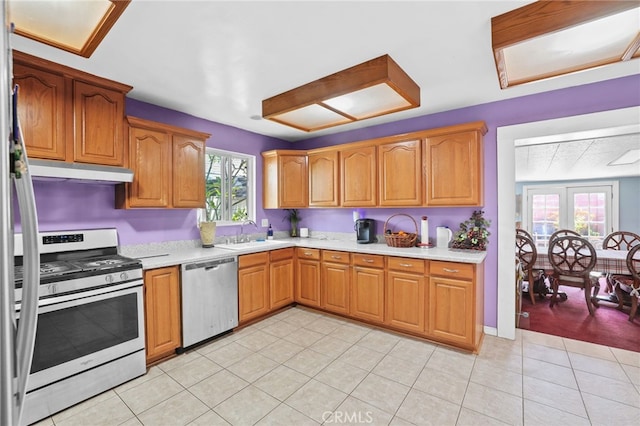 1002 N Iroquois Ave, Anaheim, CA 92801 - kitchen with appliances with stainless steel finishes, under cabinet range hood, light countertops, brown cabinetry, and light tile patterned flooring